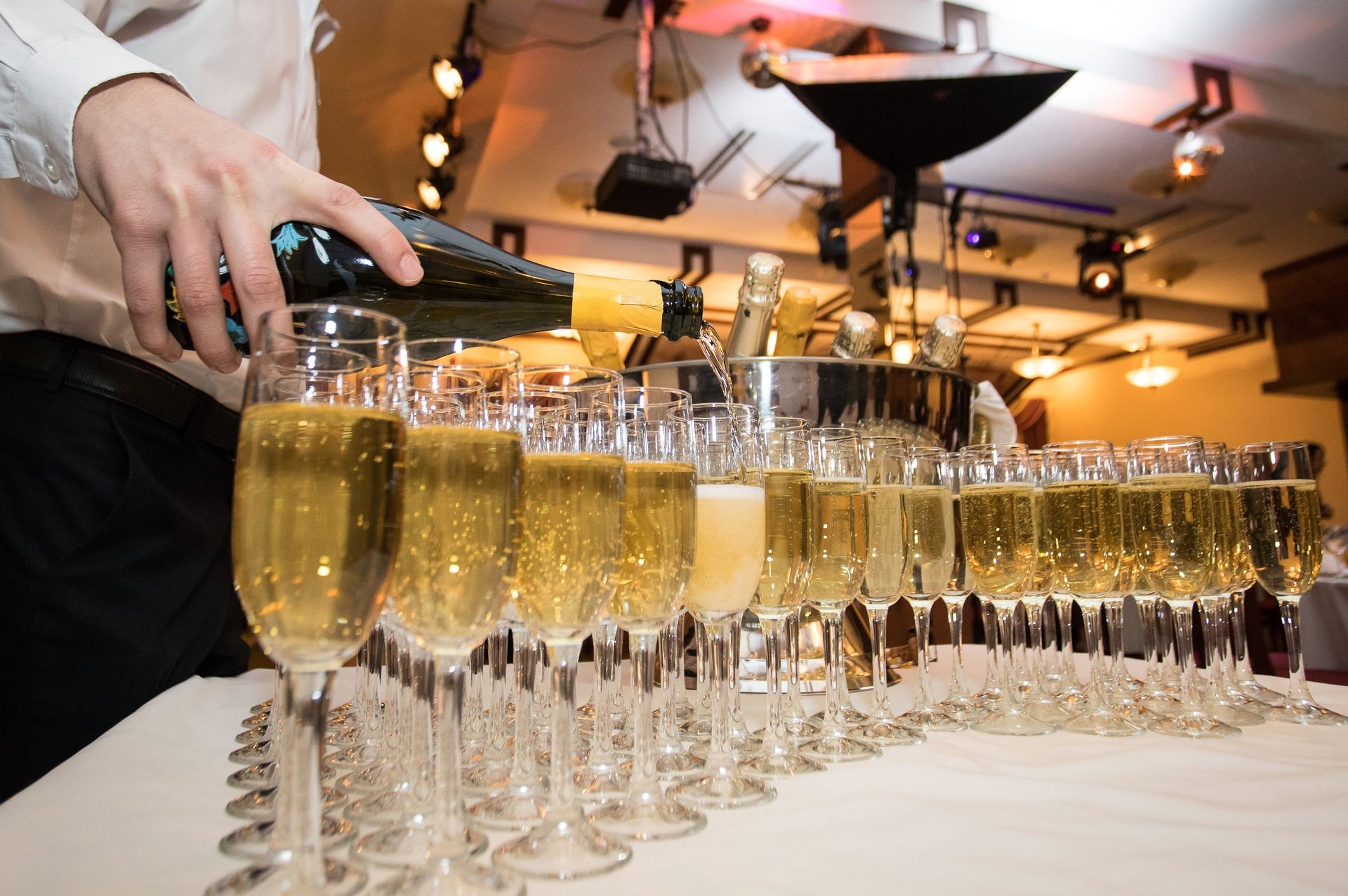 The waiter pours the champagne into the glasses at the party. Service of a holiday